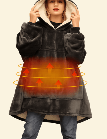 Model wearing the Warmweave™ USB Heated Oversized Hoodie Blanket in Charcoal Night with visible heating zone glow and sherpa-lined hood